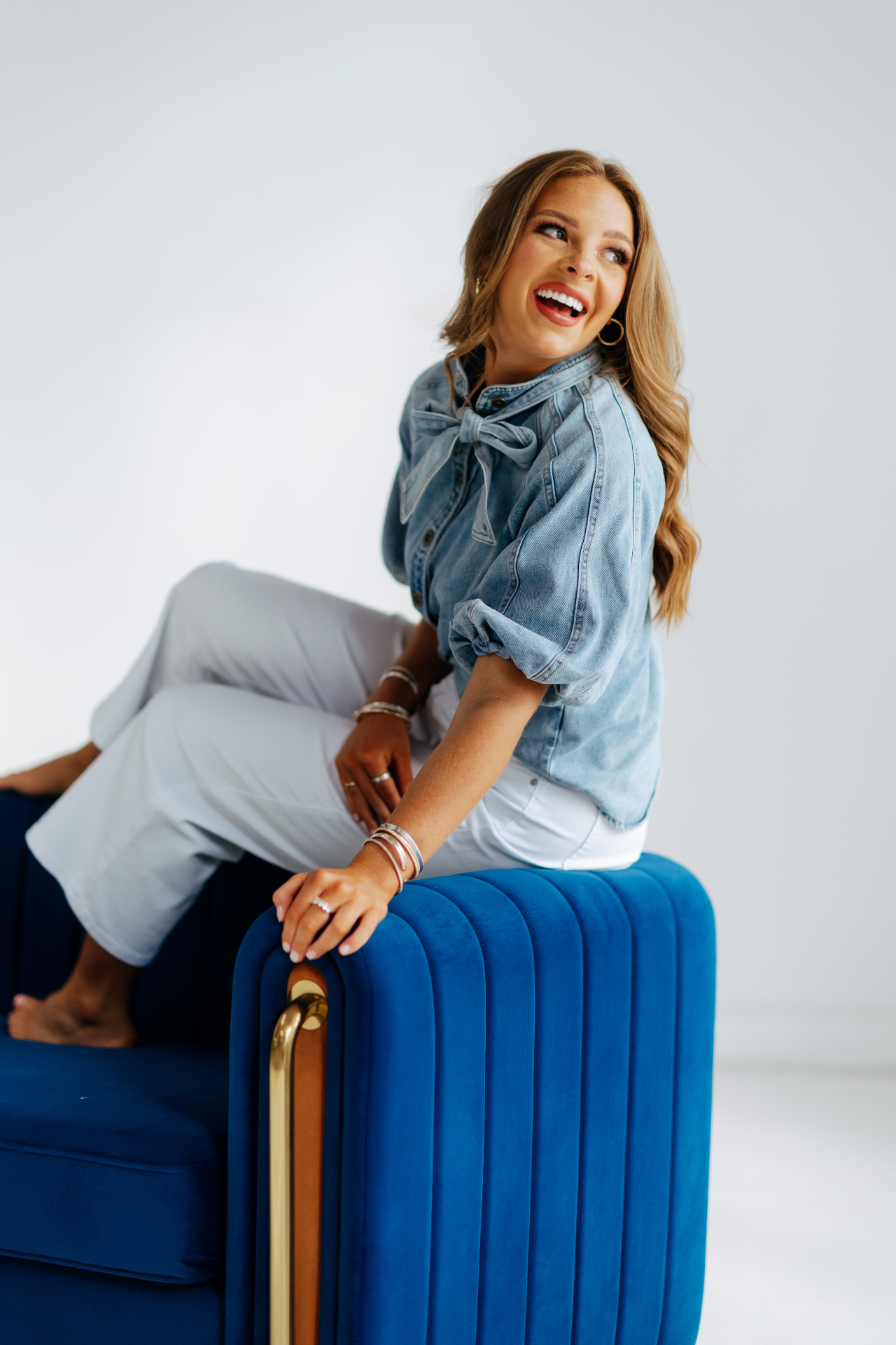 A young woman laughing on a blue velvet chair